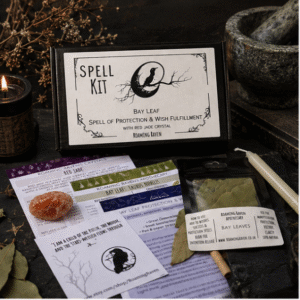 Bay leaf protection spell kit with red jade crystal, spell candle, ritual scroll, bay leaves and instructions displayed on a dark witchy altar with candles and apothecary décor.