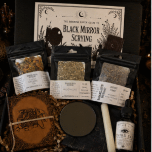 Black Mirror Scrying Kit by Roaming Raven containing a black scrying mirror, Third Eye Ritual Oil, mugwort, lavender, dream tea, ritual candle, altar cloth and illustrated guide.