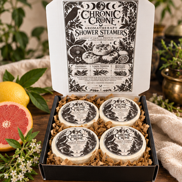 Open Chronic Crone gift box containing four wrapped shower steamers, with a black and white raven and moon design inside the lid.